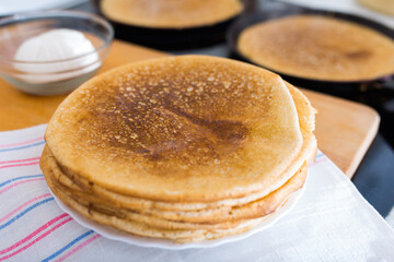 hot golden pancakes made from grain flour in kitchen while cooking on pans and on plate