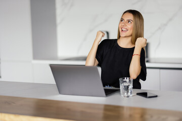 Happy woman laptop user woman celebrating good news, success, luck with winner yes hands, shouting...