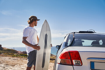Surfer man getting ready for surfing vacation and holding his surf at the beach