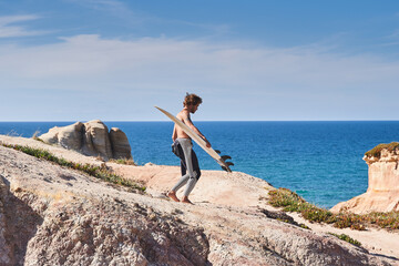 Half naked surfer walking with surf board near the ocean, while preparing for the training