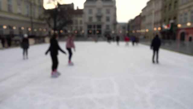 People skate on a rink. Out of focus.
