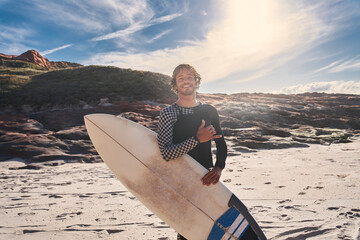 Surf beach man looking directly at the camera while posing with surf board near the ocean