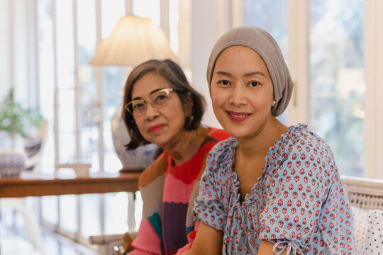 Portrait of asian senior motherand daughter sitting together on sofa at home.
