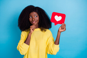 Photo of young cute girlish woman wavy hairstyle wear yellow sweater hand on chin look empty space isolated on blue color background