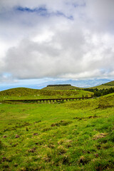 landscape with green hills, an aqueduct and cloudy sky