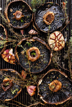 Grilled portobello mushrooms with thyme and garlic on a grill plate, top view