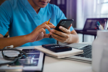 Fototapeta premium Medical technology concept. Doctor working with mobile phone and stethoscope and digital tablet laptop in modern office at hospital in morning light.