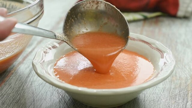 The chef serves freshly prepared cold tomato soup.
