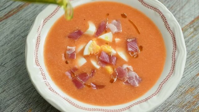 The chef pours olive oil into the freshly prepared cold tomato Spanish soup.
