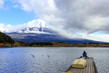  A Man Sit and Fishing Alone on wooden bridge at Kawaguchiko Lake in Japan during Sunset with Fuji Mountain Background