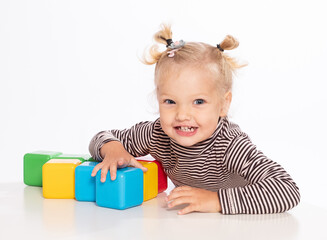 Cute little girl plays with blocks on a white background