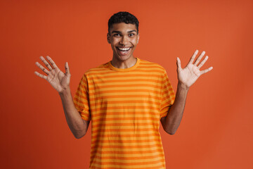 Young handsome enthusiastic african man with piercing with raised hands