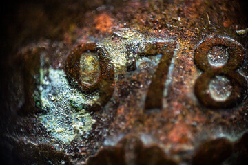Rusty texture with mold and inscription 1978 on an old coin in macro	
