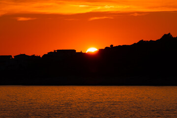 sunset over the sea with trees and houses as a silhouette and a beautiful red sky with a few clouds in Sevid, Croatia