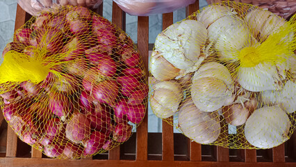 Red and white small onion in net plastic bags