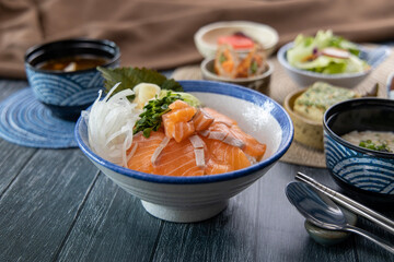 Salmon sashimi on rice and vegetable side dishes 