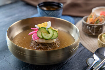 Korean traditional style naengmyeon cold noodles and various fresh vegetable side dishes