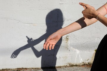 drug addict while injecting drug in his arm and shadow on the wall symbol of social hardship and...