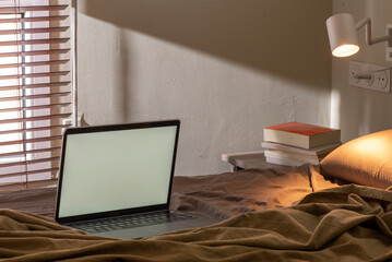 Interior de habitació, cama con ordenador, mesita con libros, luz de mesita de noche. Concepto de trabajo para casa.