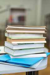 Vertical shot of the book stack on wood desk and blurred bookshelf in the library room, education background. Back to school concept