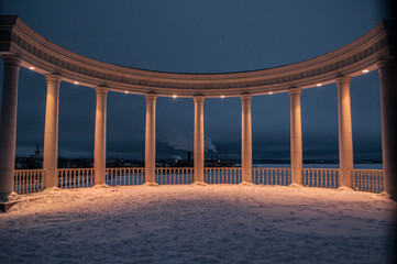 Beautiful white rotunda on the shore of the pond in the evening