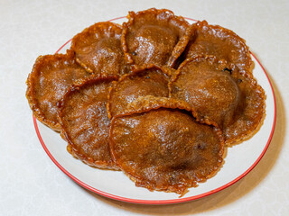 Eight traditional Indonesian palm sugar pancakes, or Kue Cucur, are served on a white plate.