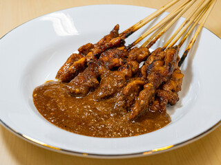 A typical serving of a chicken satay dish with peanut sauce from Madura, East Java, Indonesia.