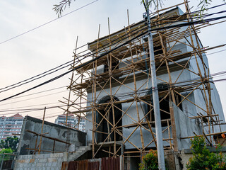 A building construction site showing an assembly of scaffolding platform made of bamboos.