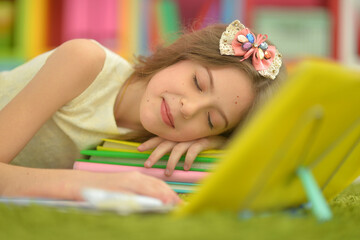 Obraz na płótnie Canvas Beautiful little girl does homework and lies on carpet
