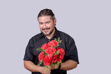 A stocky bearded man in a black polo shirt holding a bouquet of red roses. A single male in his 30s wooing and impressing a date. Isolated on a gray background. - Powered by Adobe