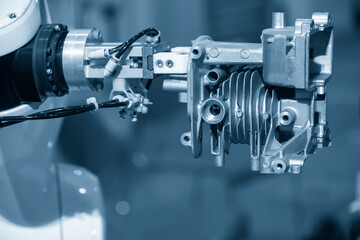 The automatic  robotic arm gripping the motorbike engine parts.