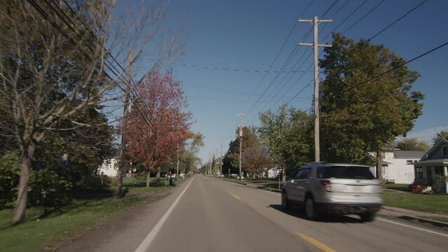 Drive along a typical street of an American town on a clear autumn day. Rear window view