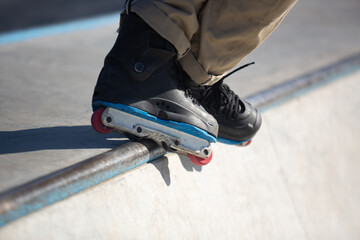 Roller blader grinding on rail in skatepark. Inline skater performing bs unity grind trick in mini...