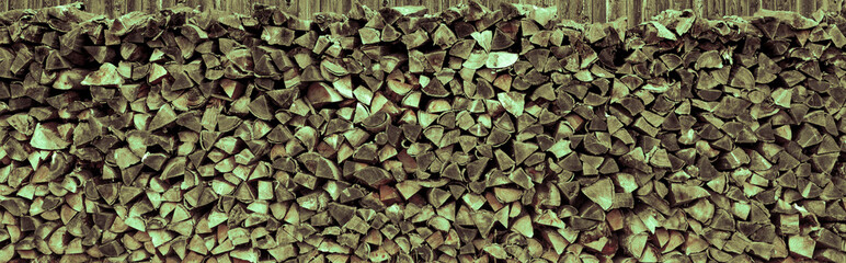 Aufgstapeltes Brennholz vor einer Holzwand © by-studio