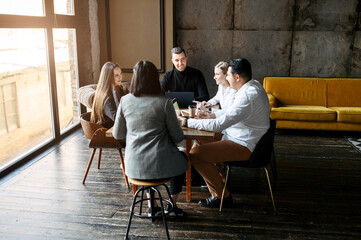People in casual clothes in an office in a loft style. They have a business meeting