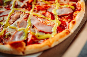 Pizza with Mozzarella cheese, ham, tomato sauce, pepper, pepperoni, sausage and mustard sauce. Italian pizza in box