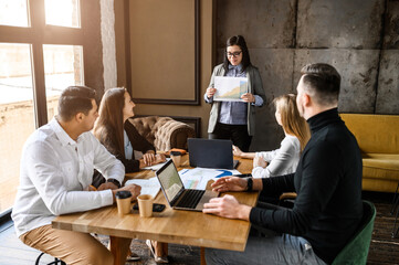 Office meeting. A woman boss explains something to her subordinates. She holds documents in her hands.