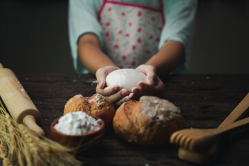 Cinematic macro shot of professional artisan baker is showing in camera just prepared fresh whole grains white bread taken out of oven in rustic bakery kitchen.