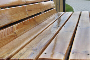 Light wooden bench in the city park close-up. Urban architecture