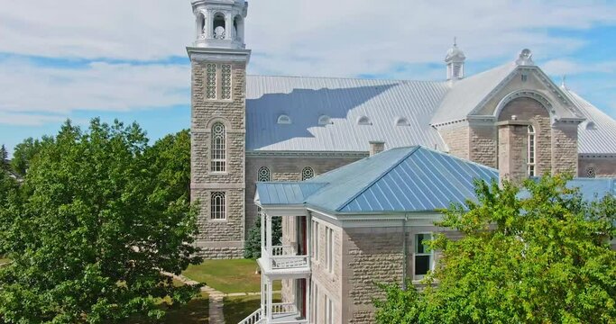 Drone crane shot by the St-Jacques de Montcalm church moving above the roof and bells revealing the village