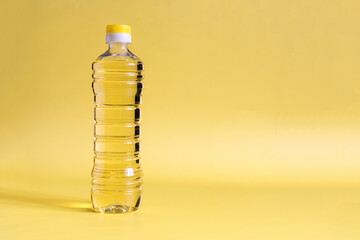 Sunflower oil in a transparent bottle close-up on a yellow background copy space