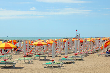 umbrellas and deck chairs without people on the beach near the sea