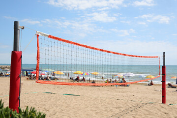 Beach volleyball net on a beach equipped with sports equipment