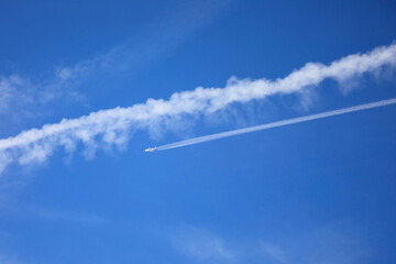 white wake and the big airliner in the ble sky and some clouds