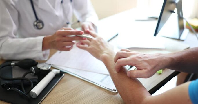 Professional doctor looking at painful dermatological infection on patient hand