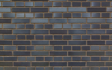 A horizontal section of a wall lined with bricks in shades of gray and brown