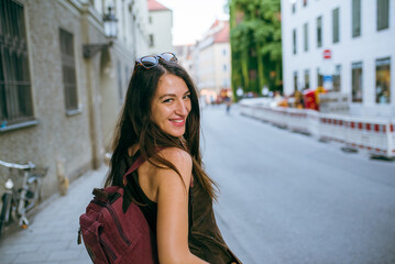 Smiling young woman carrying a backpack in the city