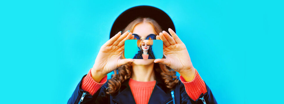 Close up of woman stretching her hands taking selfie picture with smartphone on blue background