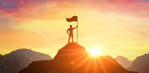 Silhouette of businessman holding flag on top mountain, sky and sun light background. Business success and goal concept. Business man with victory flag on hilltop at sunset - obrazy, fototapety, plakaty