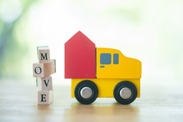Miniature red wood home on car with text of MOVE. Business moving house service concept